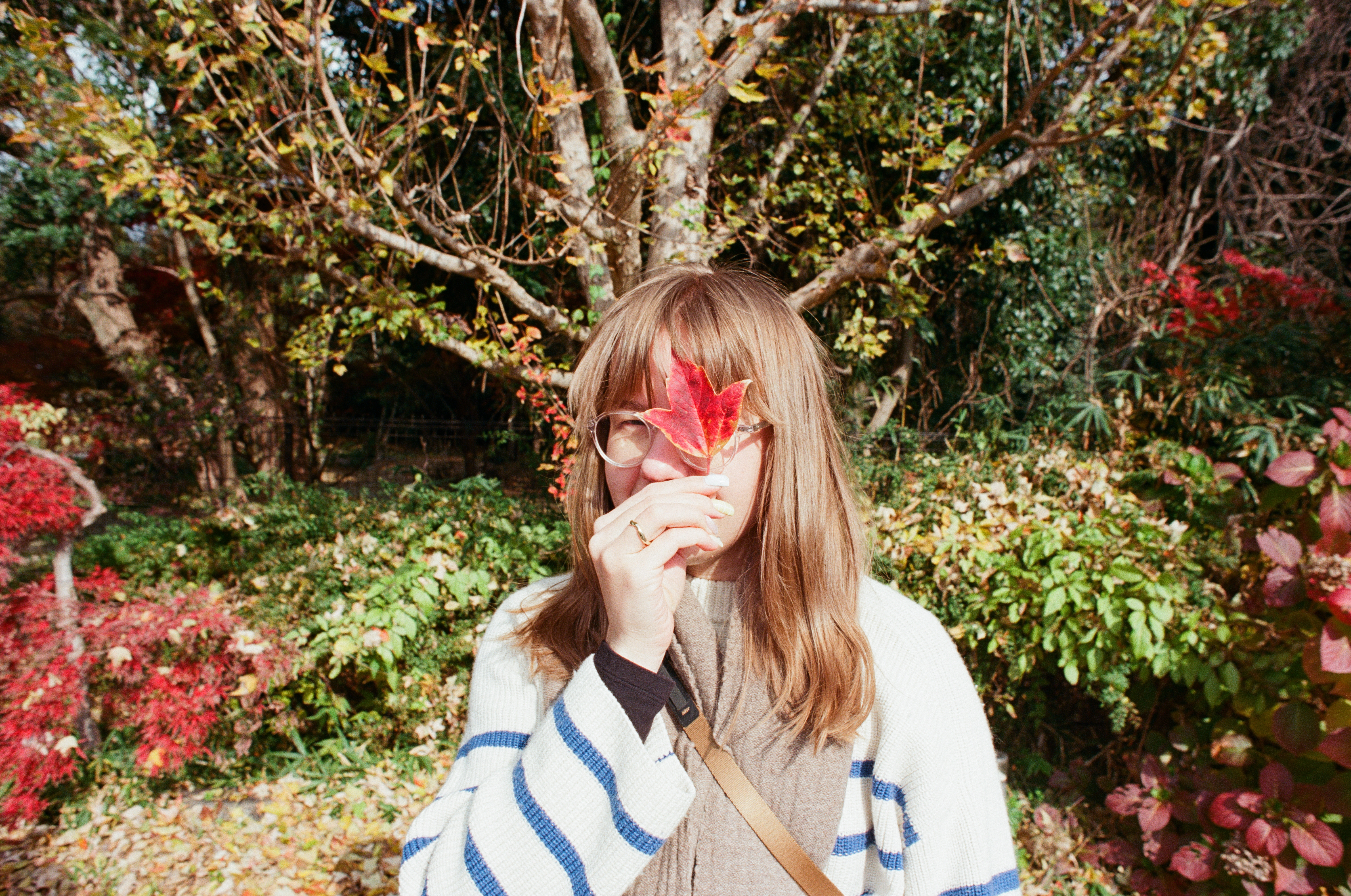 Anna holding a maple leaf in an autumn garden