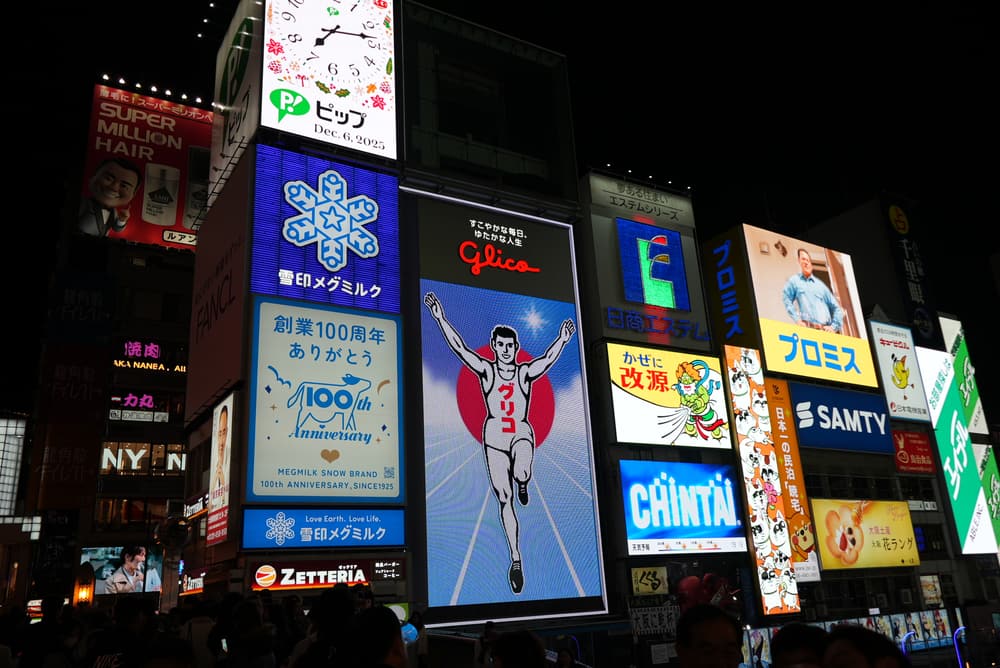 The Glico running man sign lit up over Dotonbori at night